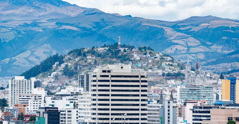 Aerial view of Quito with city buildings and the majestic Andes in the background.