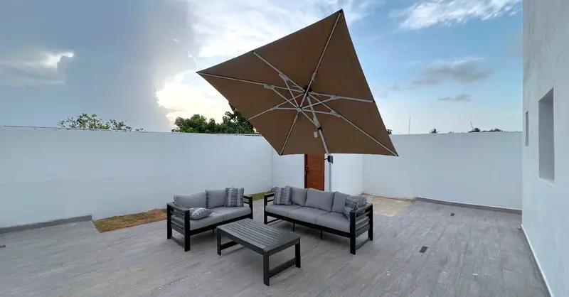Contemporary outdoor patio featuring a sofa set and umbrella under a cloudy sky.