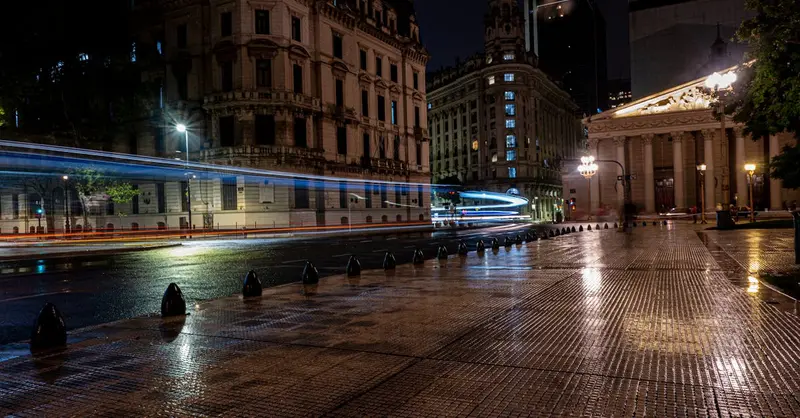 Vibrant nighttime cityscape of Buenos Aires featuring blurred traffic lights and historic architecture.