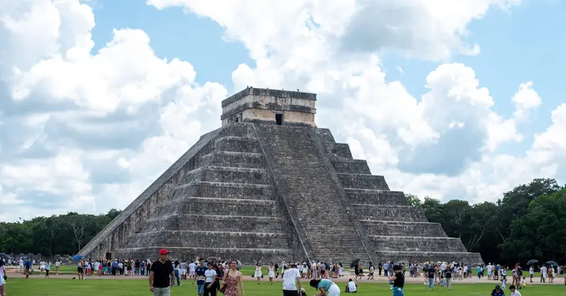 El Castillo pyramid in Chichén Itzá, Yucatán, México with tourists enjoying a sunny day.