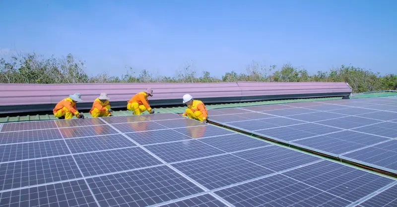 Workers installing solar panels on a sunny day, promoting renewable energy and sustainability.
