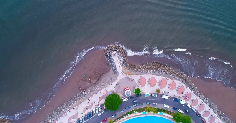 Aerial shot of a curved beachfront and ocean waves in Puntarenas, Costa Rica.