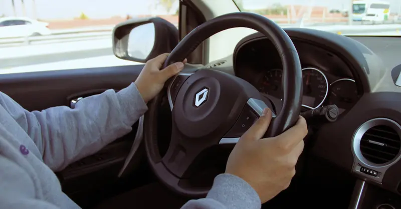 Close-up of hands on steering wheel while driving through Mexico in daylight.