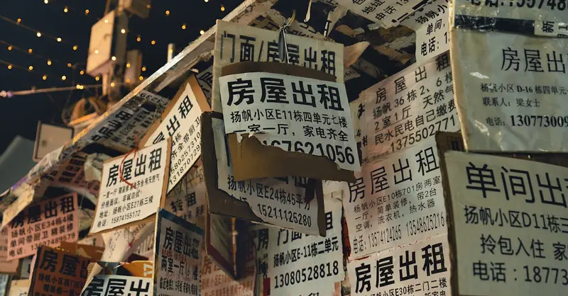 Close-up of numerous Chinese real estate posters displayed at night with warm lighting.