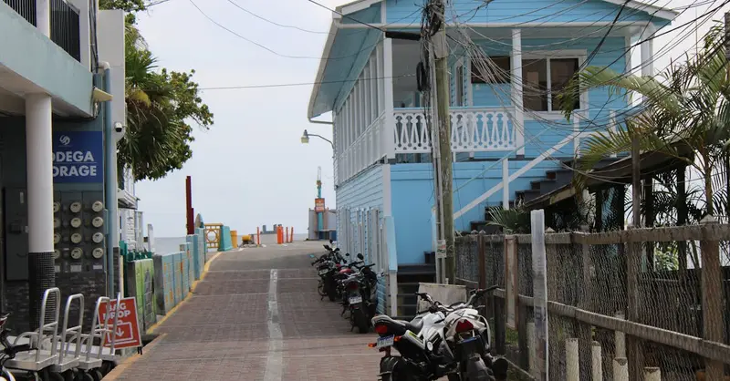 Picturesque street featuring a blue house and parked motorbikes in Utila, Honduras.