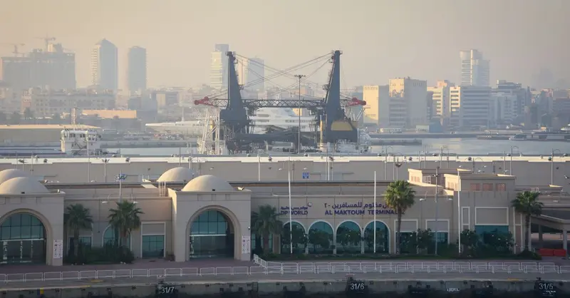 View of Al Maktoum Terminal with cranes and Dubai skyline in the background.