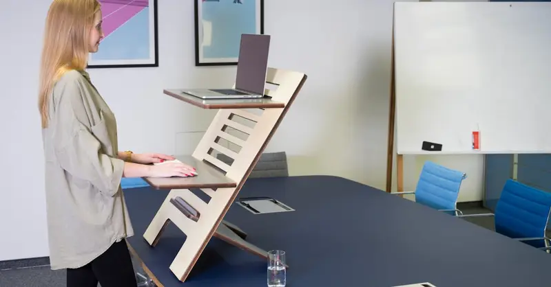 A woman uses an adjustable standing desk in a contemporary Germany office setting.