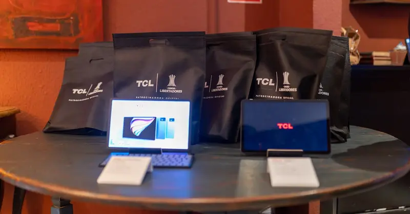 A promotional setup showcasing TCL tablets and branded gift bags on a round table indoors.
