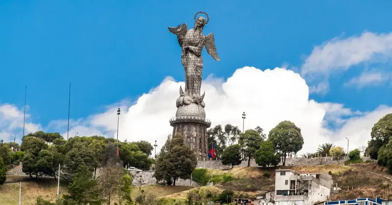 The majestic Panecillo angel statue stands over Quito, Ecuador with a clear blue sky backdrop.