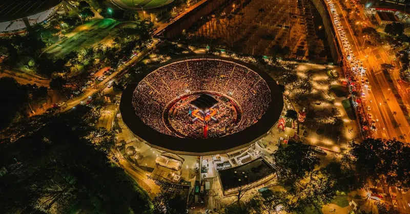 Stunning aerial shot of an illuminated stadium in Cali, Colombia at night, showcasing vibrant urban life.