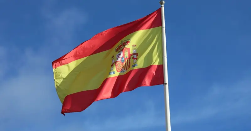 Vibrant Spanish flag waving in El Puerto de Santa María, Andalusia, against a clear blue sky.