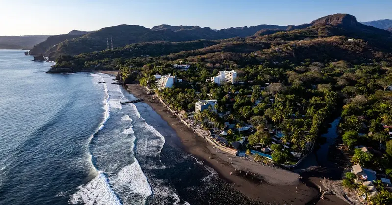 Discover the stunning coastline of El Zonte, El Salvador, captured from above showcasing the beach and lush surroundings.