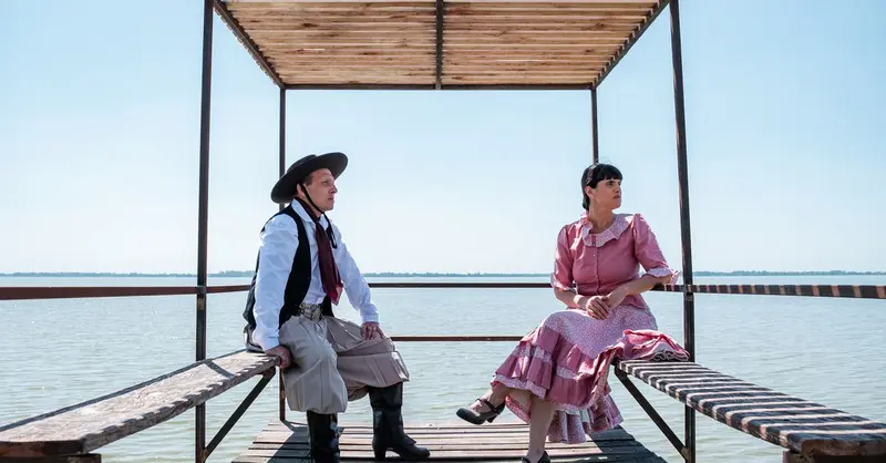 Gauchos in traditional attire relax by Chascomús Lake in Argentina.