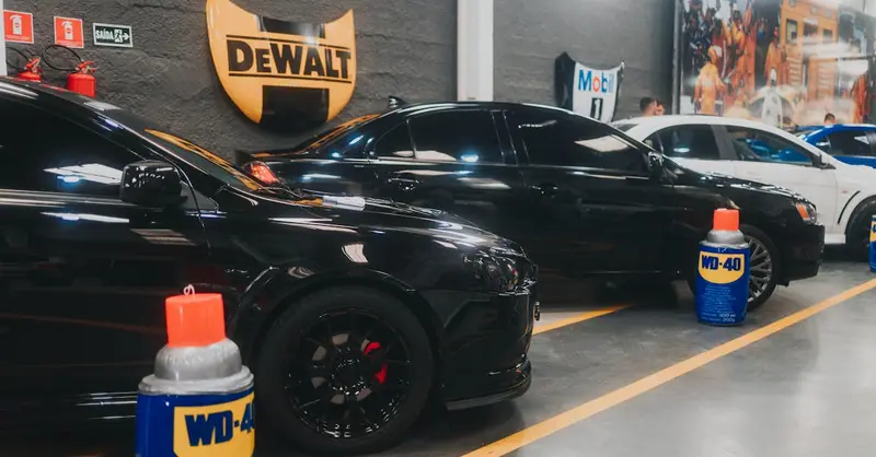 Stylish black sports cars parked in an indoor garage with WD-40 and Dewalt signage visible.