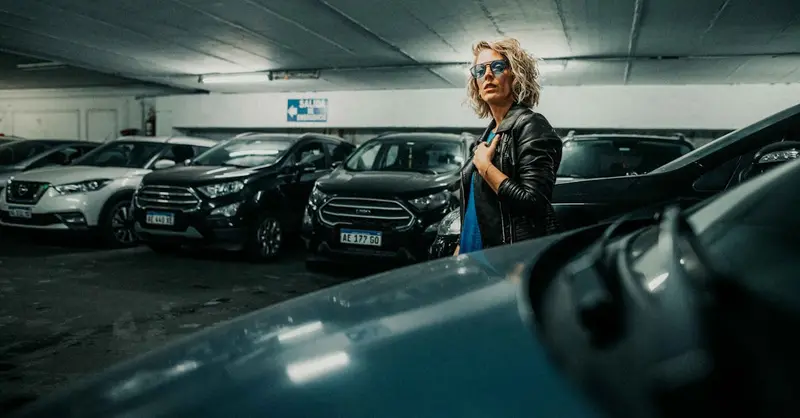 Fashionable woman wearing sunglasses in a dimly lit parking garage in Buenos Aires.