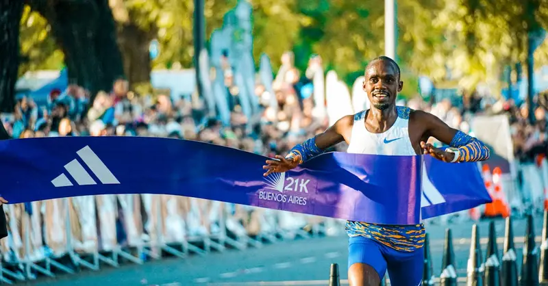 Male athlete crossing the finish line at the Buenos Aires marathon in a lively outdoor event.