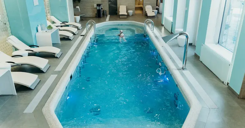 Bright indoor spa pool with lounge chairs and calm atmosphere, ideal for relaxation.