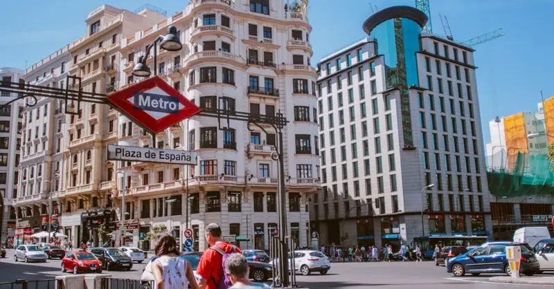 Busy urban life at Plaza de España with iconic architecture and Metro sign.