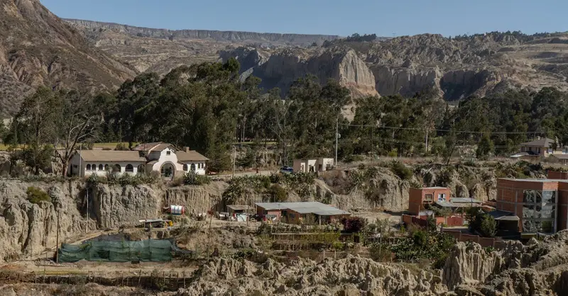 Sunlit La Paz village with dramatic eroded rock formations and lush trees.