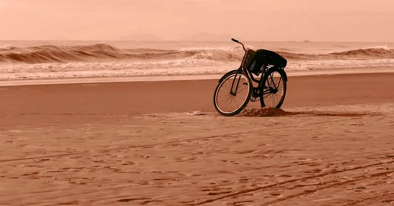 A solitary bicycle rests on a tranquil Guaratuba beach at sunset, capturing a peaceful moment.