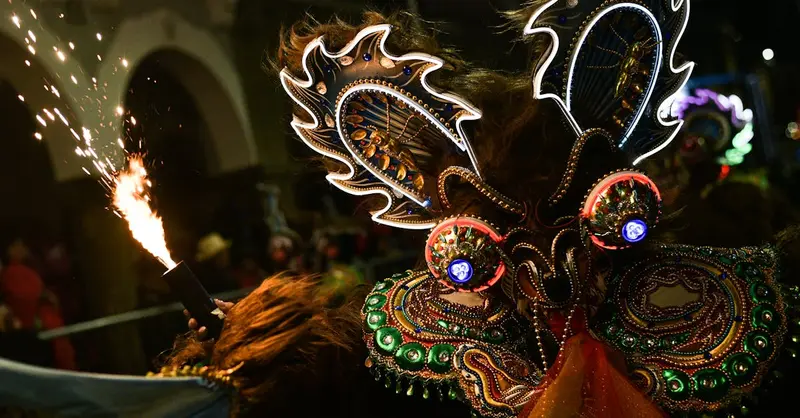 Intricate carnival mask glowing in vibrant colors during a night parade in Bolivia.