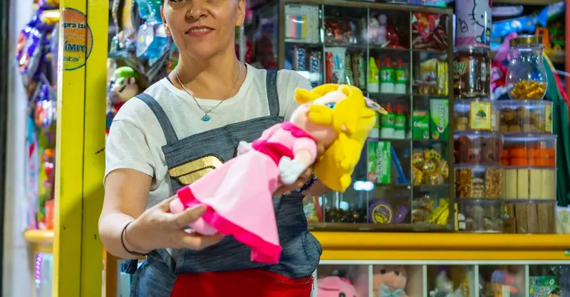Smiling woman in market stall selling colorful toys in Ciudad de México.