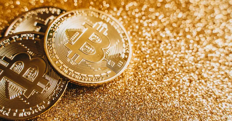 A close-up image of bitcoins placed on a sparkling gold glitter background, symbolizing cryptocurrency wealth.