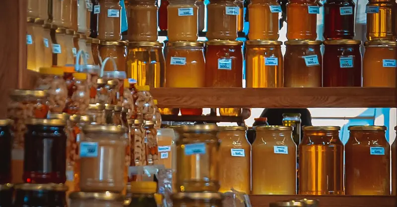 A vibrant collection of honey jars on wooden shelves, capturing the golden hues and natural sweetness.