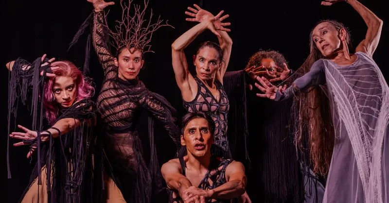 Vibrant group portrait of dancers in expressive poses on stage, showcasing emotion and drama.