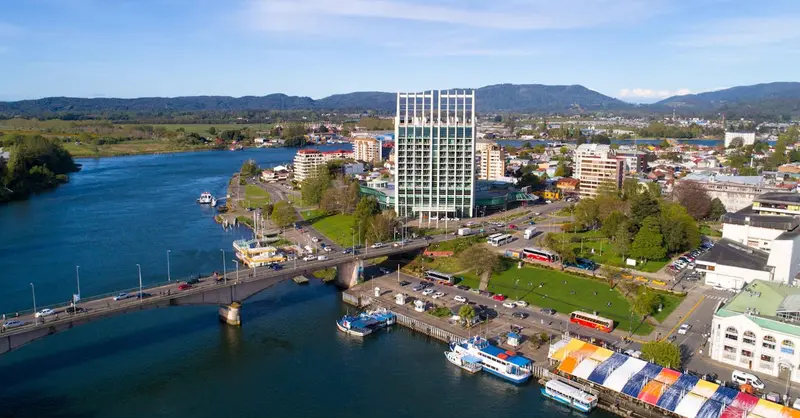 Aerial view of Valdivia, Chile, showcasing the river, bridge, and modern architecture.
