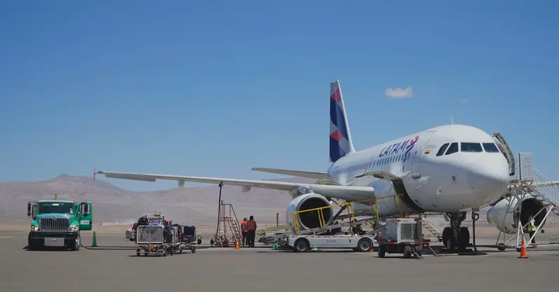 Airplane on tarmac at Chilean airport with desert background and clear skies.