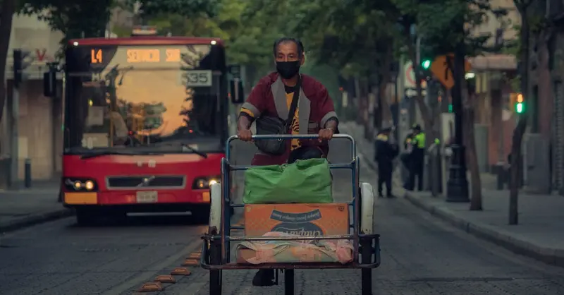A man rides a tricycle loaded with goods on a busy street in Ciudad de México, CDMX.