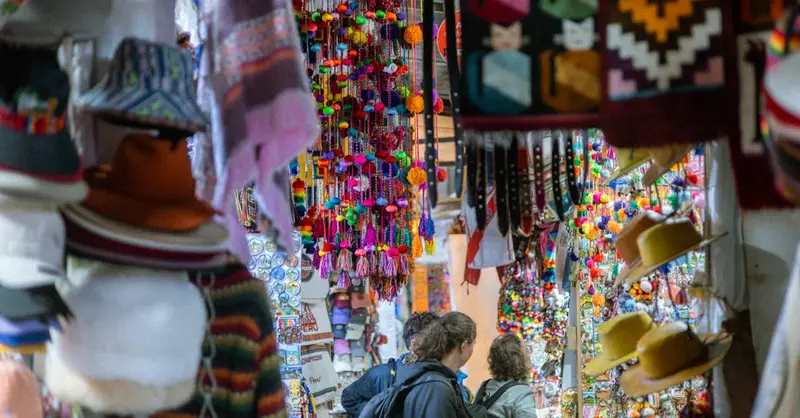 Vibrant handicrafts and tourists at a bustling market in Machu Picchu Pueblo, Cusco, Peru.