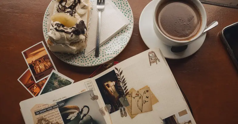 A cozy scene in a Valparaíso cafe featuring a scrapbook, coffee, and dessert on a wooden table.