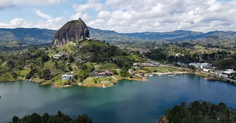 Stunning aerial view of the iconic El Peñol Rock surrounded by lush landscape and water in Guatape, Colombia.