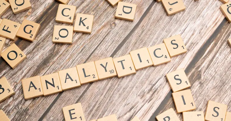 Scrabble tiles spelling 'Analytics' on a wooden surface, symbolizing data analytics concept.