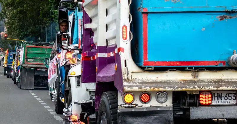 Line of colorful trucks in traffic on a Bogotá street, showcasing vibrant transportation.