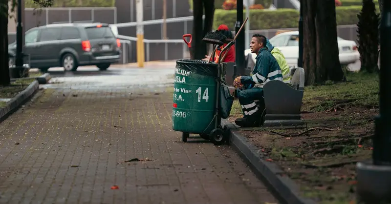 Street cleaner resting with equipment in city park, Alajuela, Costa Rica.