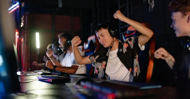 Excited gamers celebrating a win in a competitive gaming tournament with headphones.