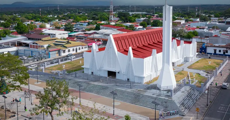 An aerial view showcasing a modern church with a red roof set against the urban landscape of Liberia, Costa Rica.