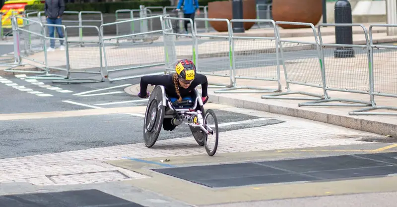 A dedicated athlete competes in a marathon using a racing wheelchair on city streets.