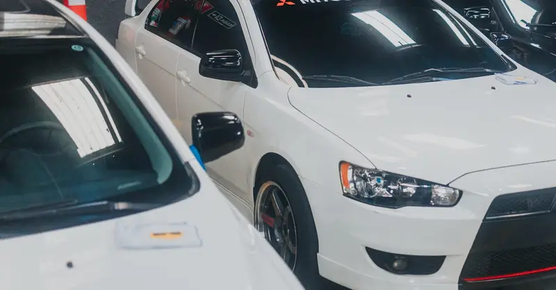 Close-up of a white Mitsubishi Lancer with decals in a garage setting.