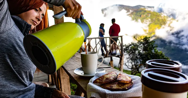 A woman pours coffee on a terrace in San José, Costa Rica, with stunning mountain views.