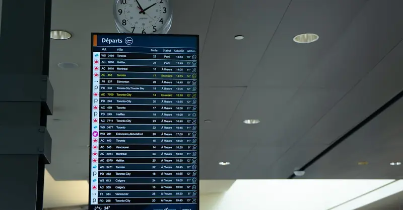 Airport departure screen showing various flight schedules and times with a wall clock above.
