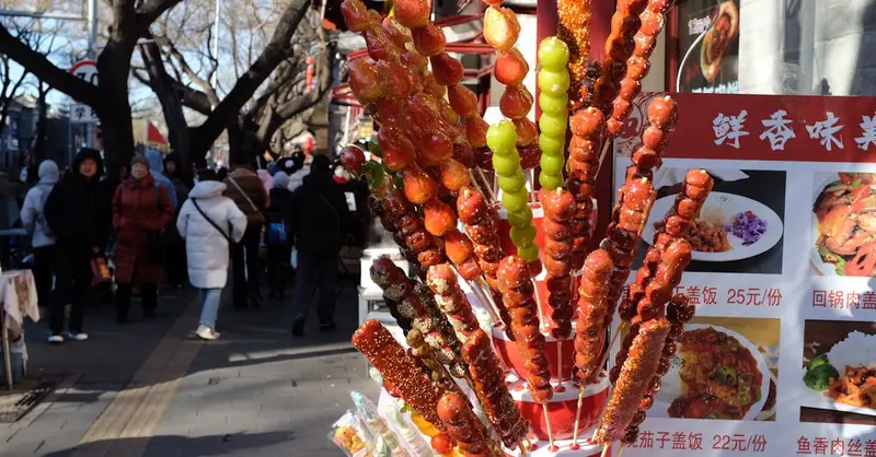 Colorful candied fruit skewers displayed at a bustling outdoor street market.