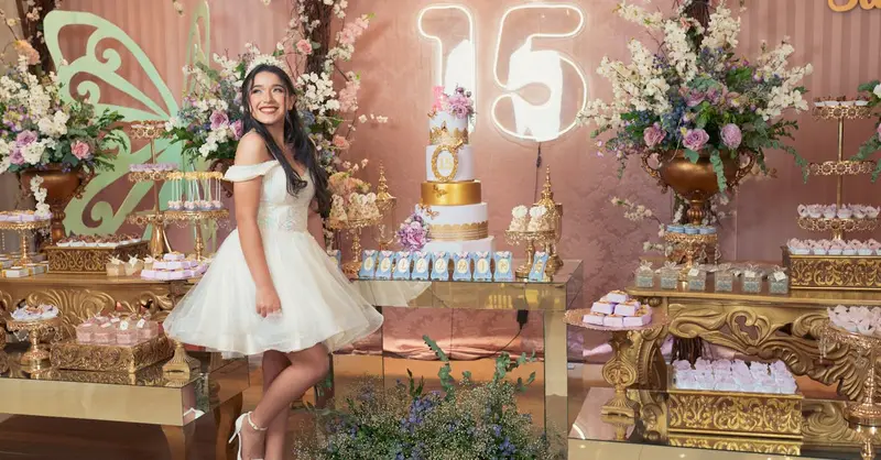 A beautiful quinceañera party setup with an elegant cake, floral decor, and a young woman in a white dress.