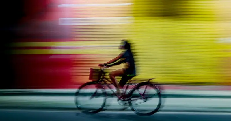 Dynamic motion blur of a person cycling past colorful shutters at night in Parintins, Amazonas, Brazil.