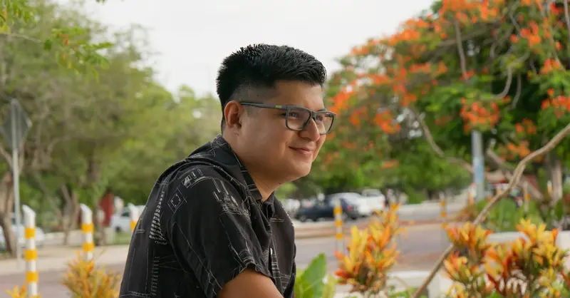 Portrait of a man with glasses smiling in a vibrant park setting in Merida, Yucatan, Mexico.