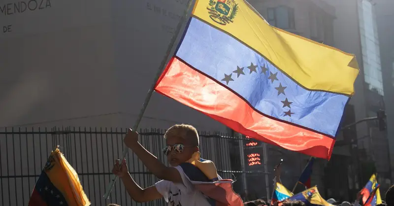A young boy waves the Venezuelan flag during a vibrant street protest.