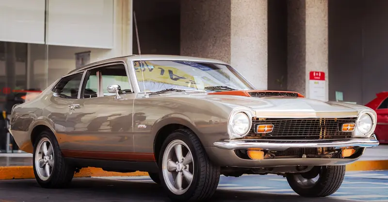 A classic vintage car parked outside a dealership, showcasing retro design and style.